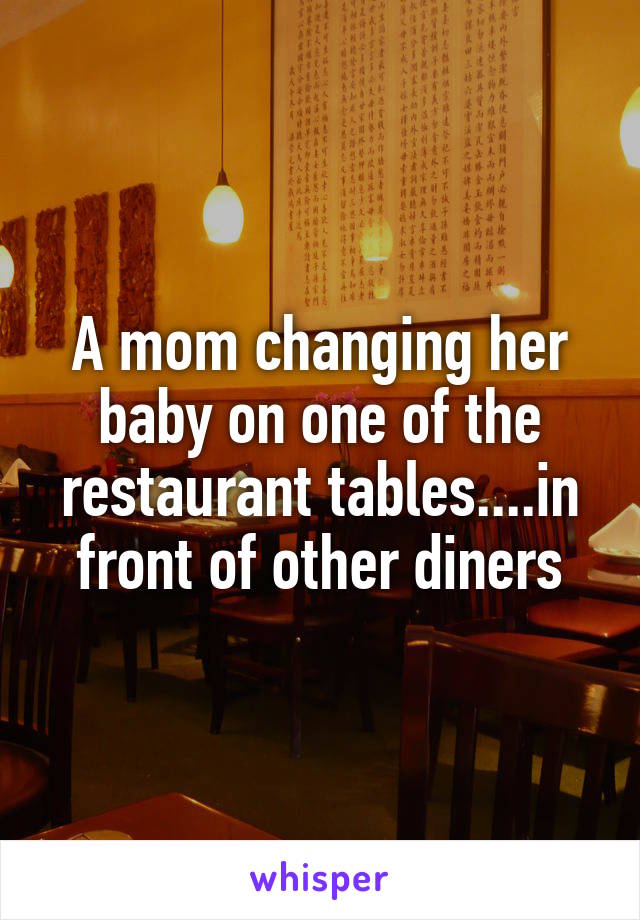 A mom changing her baby on one of the restaurant tables....in front of other diners