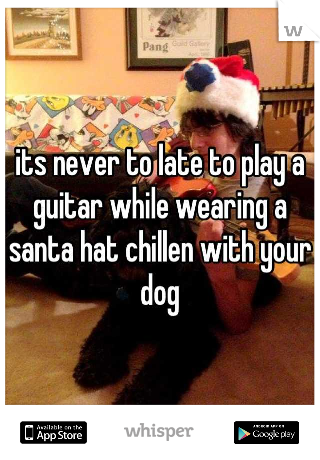 its never to late to play a guitar while wearing a santa hat chillen with your dog