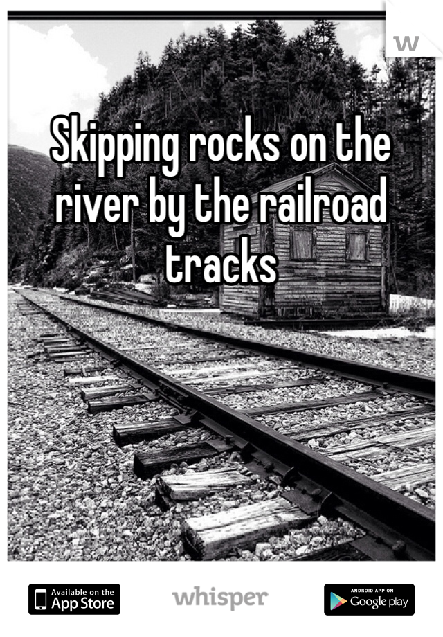 Skipping rocks on the river by the railroad tracks