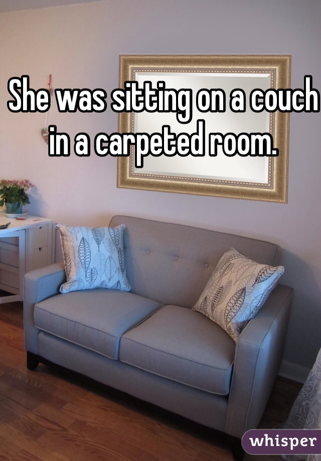 She was sitting on a couch in a carpeted room.