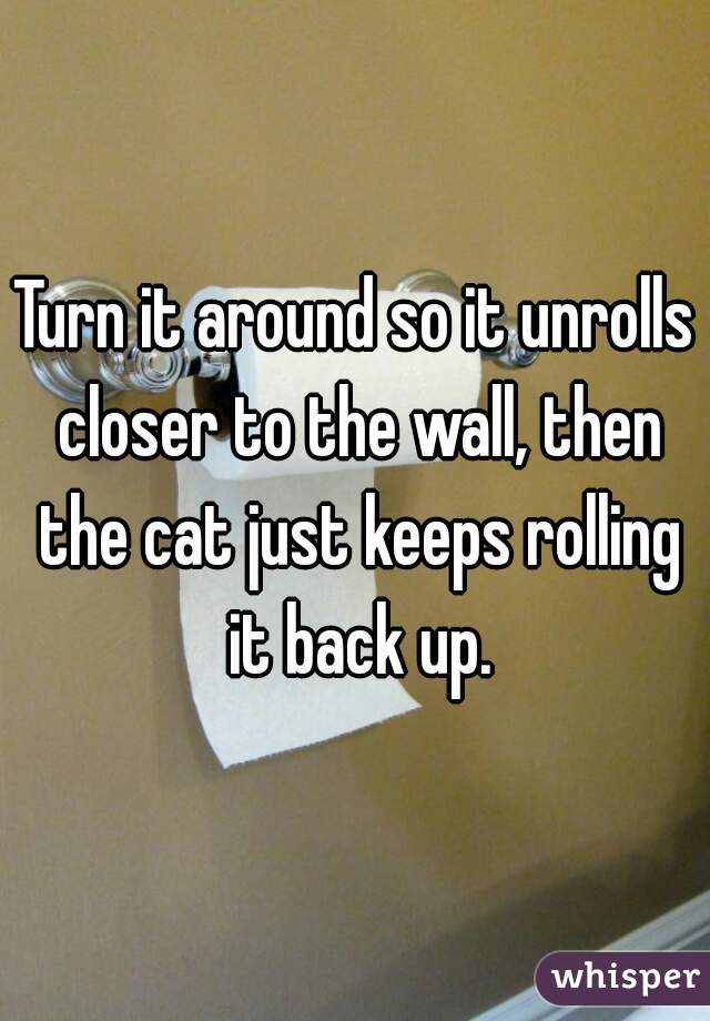 Turn it around so it unrolls closer to the wall, then the cat just keeps rolling it back up.