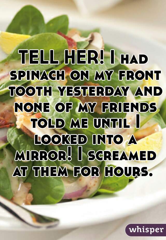 TELL HER! I had spinach on my front tooth yesterday and none of my friends told me until I looked into a mirror! I screamed at them for hours. 