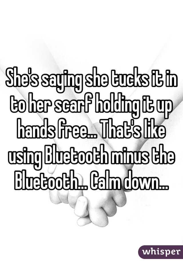 She's saying she tucks it in to her scarf holding it up hands free... That's like using Bluetooth minus the Bluetooth... Calm down...