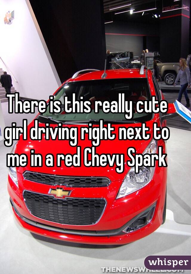 There is this really cute girl driving right next to me in a red Chevy Spark 