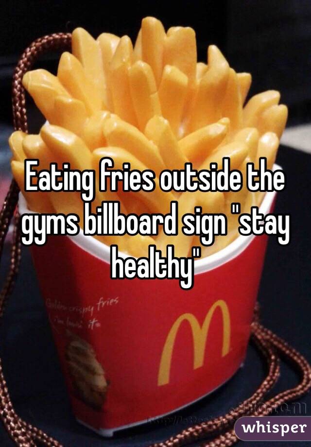 Eating fries outside the gyms billboard sign "stay healthy"