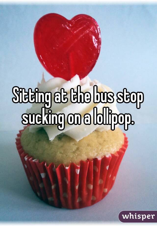 Sitting at the bus stop sucking on a lollipop. 