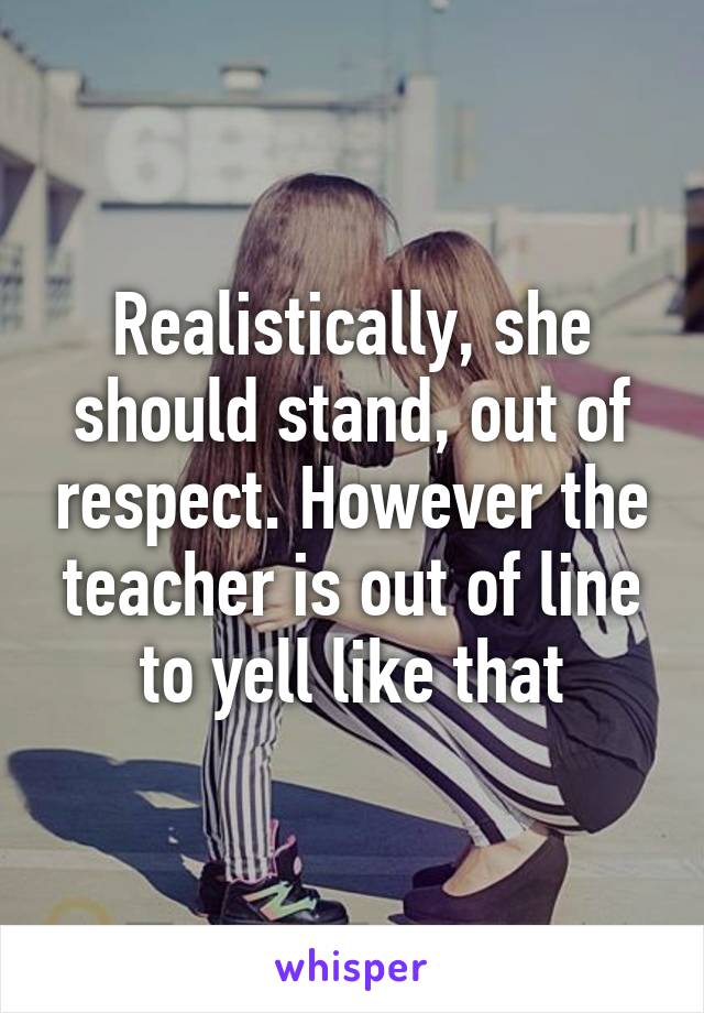 Realistically, she should stand, out of respect. However the teacher is out of line to yell like that