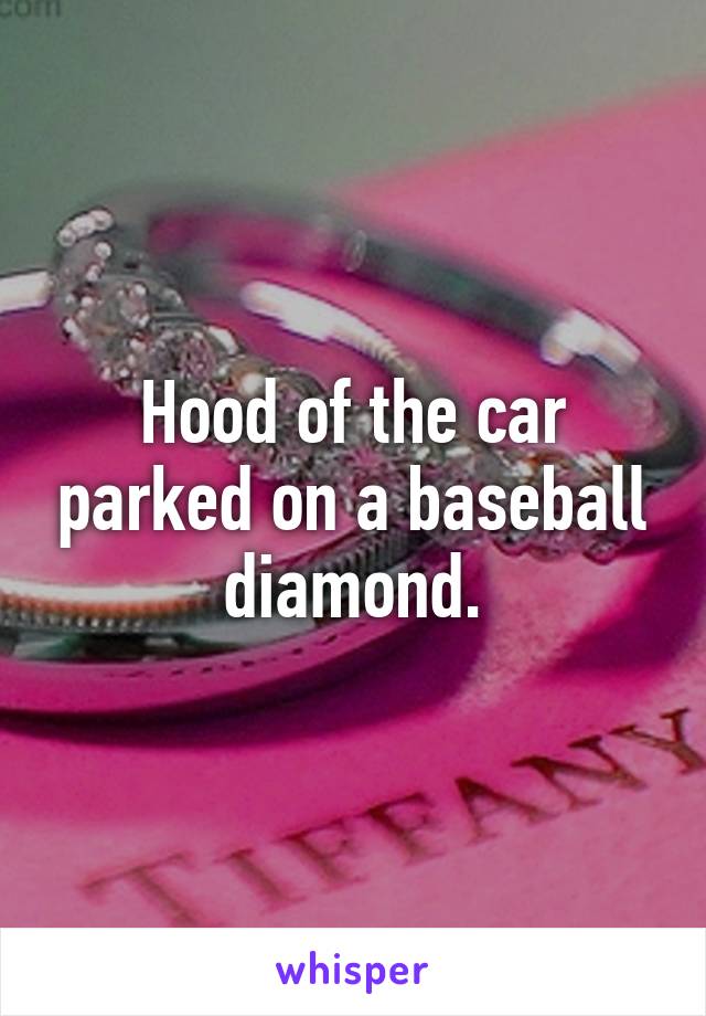 Hood of the car parked on a baseball diamond.
