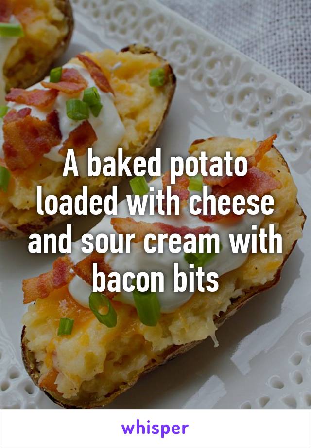 A baked potato loaded with cheese and sour cream with bacon bits