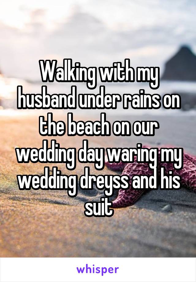 Walking with my husband under rains on the beach on our wedding day waring my wedding dreyss and his suit