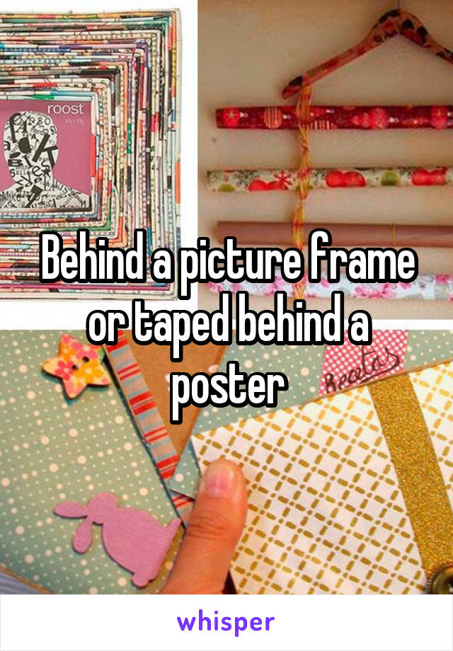 Behind a picture frame or taped behind a poster