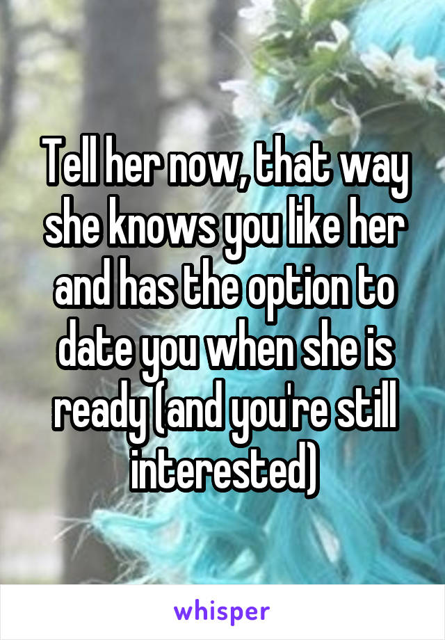Tell her now, that way she knows you like her and has the option to date you when she is ready (and you're still interested)