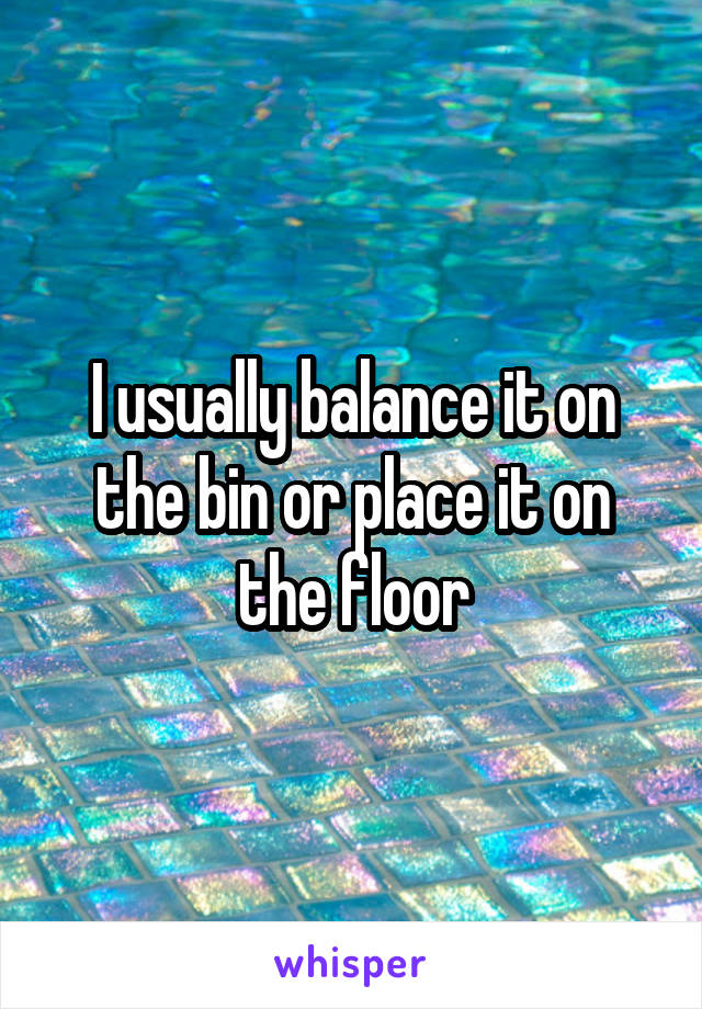 I usually balance it on the bin or place it on the floor