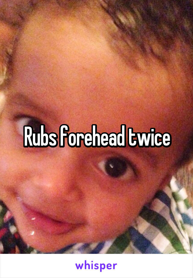 Rubs forehead twice