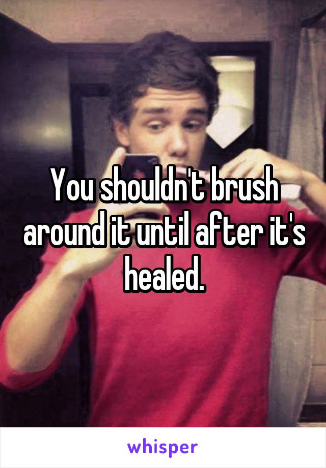 You shouldn't brush around it until after it's healed.