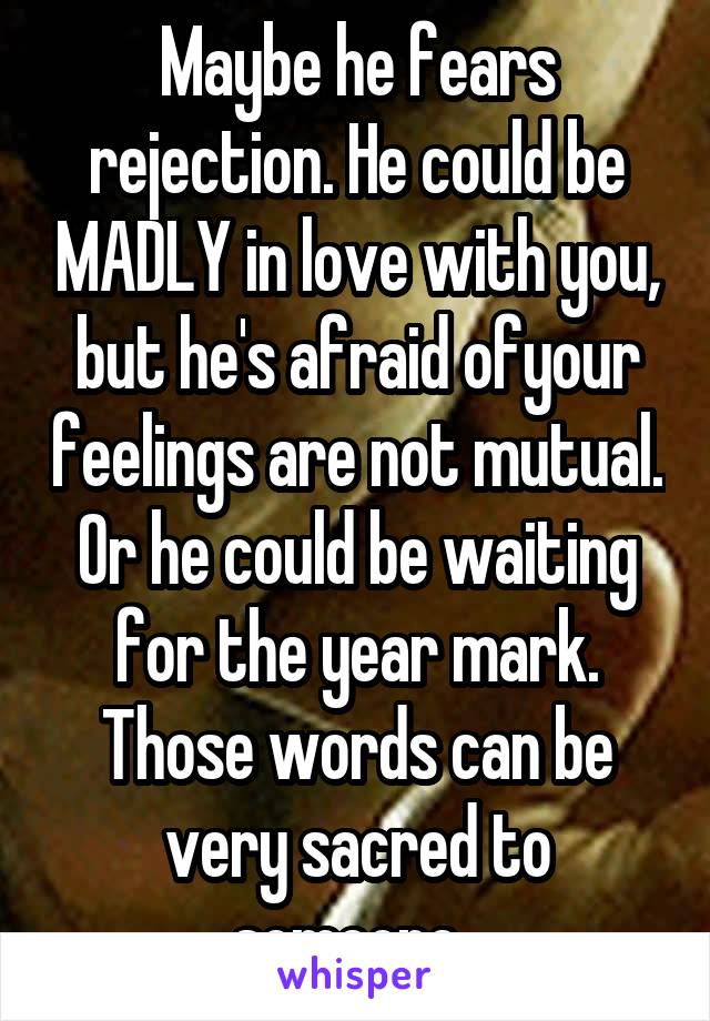 Maybe he fears rejection. He could be MADLY in love with you, but he's afraid ofyour feelings are not mutual. Or he could be waiting for the year mark. Those words can be very sacred to someone. 