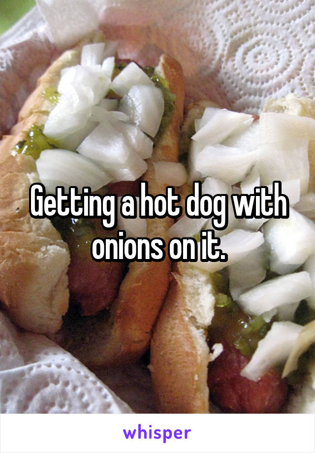 Getting a hot dog with onions on it.