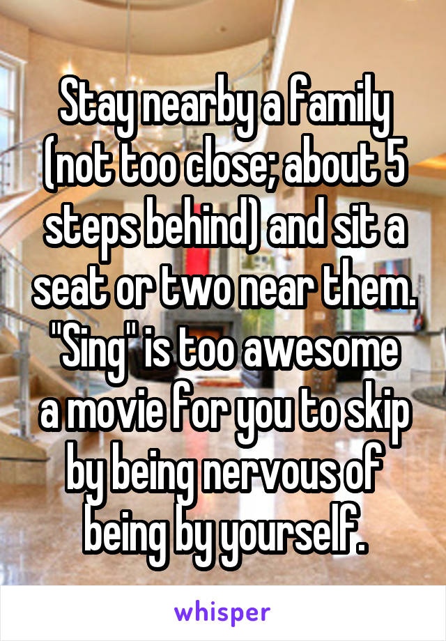 Stay nearby a family (not too close; about 5 steps behind) and sit a seat or two near them.
"Sing" is too awesome a movie for you to skip by being nervous of being by yourself.